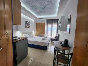 um quarto de hotel com uma cama, uma mesa e cadeiras em The Blue Beach Apartments em Nea Peramos