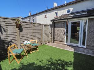 a small yard with a table and chairs and a fence at Little Gem in Maryport