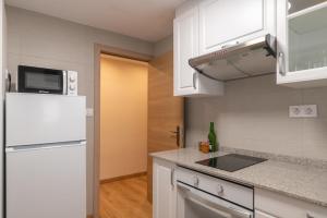 a kitchen with white cabinets and a white refrigerator at Belmonte, apartamento en Ribadesella in Ribadesella