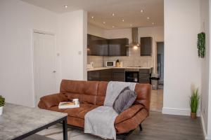 a living room with a brown couch and a kitchen at Enchanting and welcoming space in Aintree