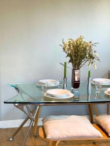 uma mesa de vidro com pratos e um vaso com flores em Home in Chiswick Homefields em Londres