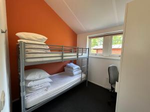 ein Schlafzimmer mit einem Etagenbett mit einer orangefarbenen Wand in der Unterkunft Modern Vacation home - Near the Wadden Sea in Tzummarum + 26 Fotos