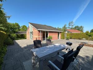 eine Terrasse mit einem Tisch und Stühlen sowie ein Haus in der Unterkunft Modern Vacation home - Near the Wadden Sea in Tzummarum