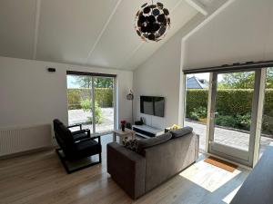uma sala de estar com um sofá e uma televisão em Modern Vacation home - Near the Wadden Sea em Tzummarum