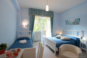 ein blaues Schlafzimmer mit 2 Betten und einem Fenster in der Unterkunft Magna Cura in Rom