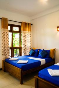 a bedroom with two beds with blue sheets and a window at Sigiri Sierra View Resort in Sigiriya