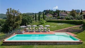 een zwembad met stoelen en parasols bij Villa Violetto in Gaiole in Chianti