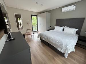 een slaapkamer met een groot wit bed en een bureau bij The Wantage Suites in Johannesburg