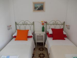 two beds in a room with red and orange pillows at Hotel Europa in Ischia