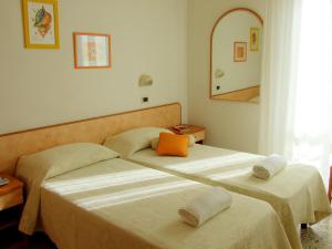 two beds in a room with a mirror at Hotel Manuela in Cervia