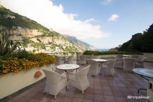 un patio con tavoli, sedie e una montagna di Luxury Suite Royal Positano a Positano
