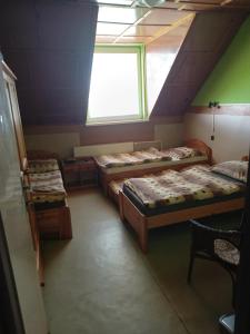 a attic room with three beds and a window at Turistika ubytovňa sivá brada in Spišské Podhradie