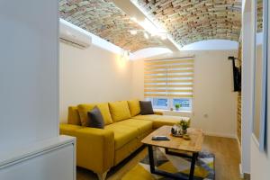 - un salon avec un canapé jaune et une table dans l'établissement All seasons apartments Sarajevo with free parking, à Sarajevo