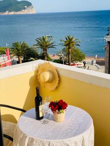 a table with a bottle of wine and a basket of flowers at Miomir Perazic Apartments in Petrovac na Moru
