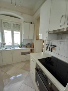 cocina con armarios blancos y fogones negros en Comfy Apartment in Rijeka center en Rijeka