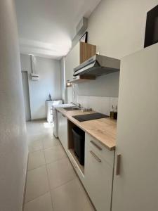 een keuken met witte kasten en een aanrecht bij Bel appartement à 15 min de Lyon in Saint-Fons