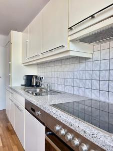 Homely Stay Apartment 3 في سانت بولتن: مطبخ مع دواليب بيضاء ومغسلة