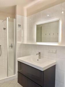 ein weißes Bad mit einem Waschbecken und einer Dusche in der Unterkunft Homely Stay Apartment 3 in Sankt Pölten