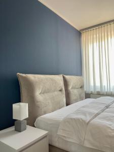 Homely Stay Apartment 3 في سانت بولتن: غرفة نوم بسرير ابيض وجدار ازرق