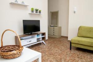 a living room with a television and a green couch at New Zeusplace apartment with private parking Paralia Katerini in Paralia Katerinis