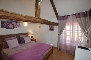 1 dormitorio con cama morada y ventana en La libellule argentée, en Le Teilleul