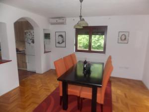 a dining room with a black table and orange chairs at Kuća za odmor V&E in Bihać