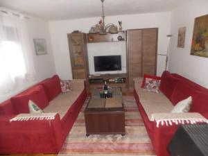 een woonkamer met twee rode banken en een tv bij Kuća za odmor V&E in Bihać