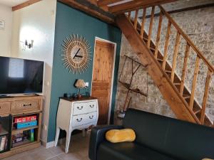 a living room with a couch and a staircase at Maison de pêcheur charmante et atypique en pierre, 1 min de marche de la mer in Saint-Aubin-sur-Mer