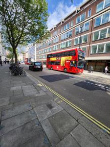 a red double decker bus driving down a city street at Top Floor Room in Baker St in London