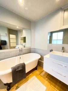 a bathroom with a large white tub and a sink at Home in Chiswick Homefields in London