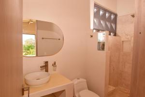 een badkamer met een wastafel, een toilet en een spiegel bij ILUKA VILLAS in Coveñas