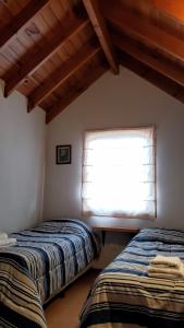 twee bedden in een kamer met een raam bij Cálido departamento 2 dormitorios - Céntrico in San Martín de los Andes