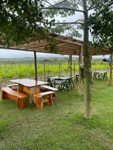 a picnic table and benches under a wooden pavilion at Chalé Roma Negra in Morro do Chapéu
