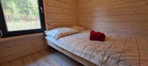 Cama en habitación de madera con 2 almohadas rojas en Pietraszówka, en Piertanie