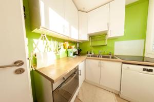 a kitchen with white cabinets and green walls at La Cuccia - Fully furnished apartment close to metro and Olympic venues in Châtillon