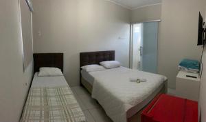 HOTEL LIFE IJUI في ليجوي: غرفة نوم بسريرين وكابينة حمراء