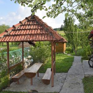 a wooden gazebo with a bench and a table at Vikendica Farah 
