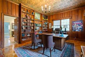 a home office with a desk and chairs and bookshelves at Luxury Farmhouse in the Heart of Historic Downtown in Cartersville