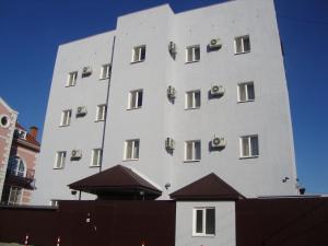un edificio alto y blanco con sillas. en Residence Keruen en Atyraū