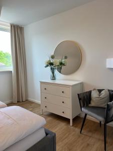 a bedroom with a dresser with a mirror and a chair at Ferienwohnung Bodenseeglück in Friedrichshafen