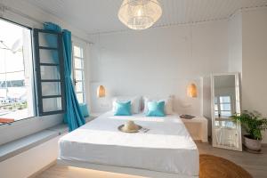 a white bedroom with a large bed with blue pillows at The White Rose Apartment in Poros