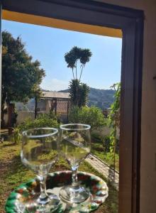 dos copas de vino sentadas en un plato en una ventana en Mini Casarão en São Bento do Sapucaí