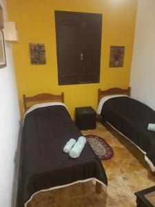 2 łóżka w pokoju z żółtymi ścianami w obiekcie Mini Casarão w mieście São Bento do Sapucaí