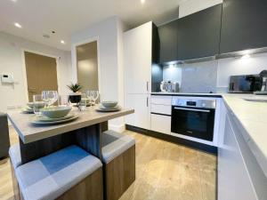 Brand New Apartment in the Heart of Chelmsford في تشيلمسفورد: مطبخ مع طاولة مع كؤوس للنبيذ عليه