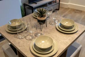 a table with plates and wine glasses on it at Brand New Apartment in the Heart of Chelmsford in Chelmsford