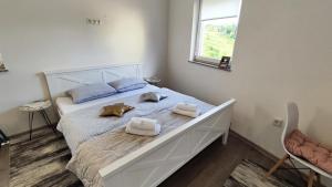 sypialnia z dużym białym łóżkiem z ręcznikami w obiekcie Apartmani Toki Balkana w mieście Mrkonjić Grad