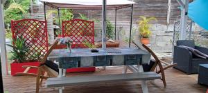 una mesa y sillas en un patio con sombrilla en Beau F2 classé, vue mer, spa, jardin, bateau, en Le Robert
