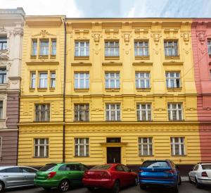 a yellow building with cars parked in front of it at Luxury Prague Riverside Apartment in Prague