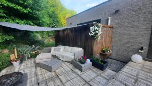 a patio with a white couch and chairs on a wooden deck at La Maison De Marie in Binche +34 photos