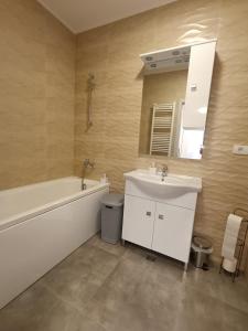 uma casa de banho com um lavatório, uma banheira e um espelho. em Apartament Genius 2 em Ploiesti